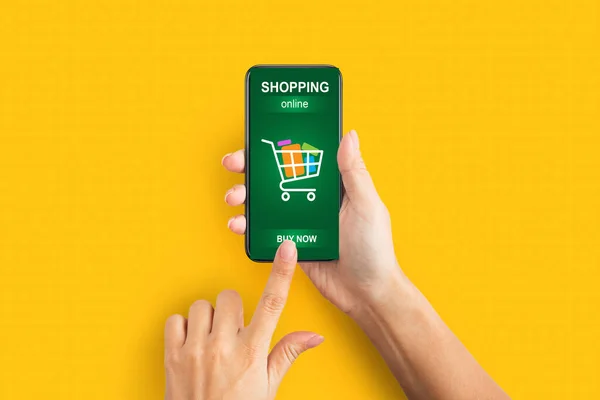 Kobiece ręce ze smartfonem Zakupy online za pomocą aplikacji, Żółte tło — Zdjęcie stockowe