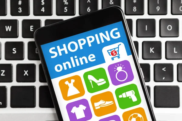 Smartphone med program för online shopping ligger på datorns tangentbord — Stockfoto