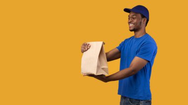 Mutlu gülümseyen siyah teslimatçı paketini tutuyor.