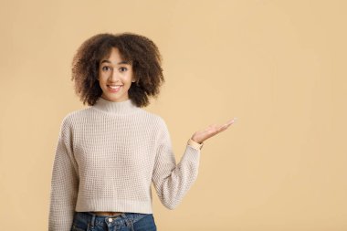 Özel bir şey ve tavsiye. Süveter giymiş neşeli Afro-Amerikan kadın portresi boş bir alanda duruyor.