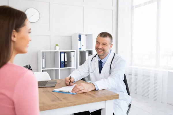 Uśmiechnięty doświadczony lekarz rozmawiający ze swoim pacjentem — Zdjęcie stockowe