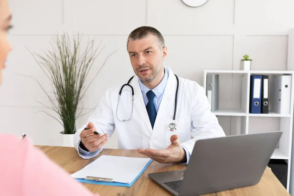 Серйозний досвідчений лікар розмовляє зі своїм пацієнтом — стокове фото