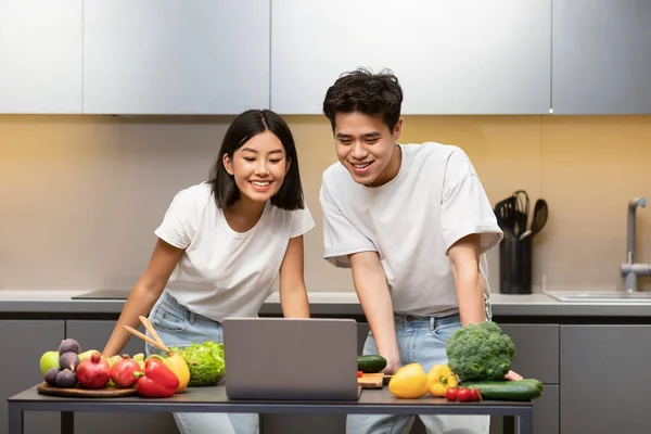 Happy Chinese Couple Using Laptop Cooking Dinner In Modern Kitchen — Stock Photo, Image