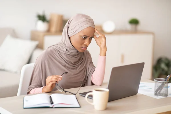 Fáradt fekete nő hidzsáb elmulasztja betartani a határidőt, nehézségek üzleti projekt közelében laptop otthon — Stock Fotó