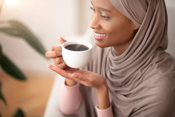 İyi sabahlar. Geleneksel tesettürlü mutlu Müslüman kadın evde koyu sade kahve içiyor. — Stok fotoğraf