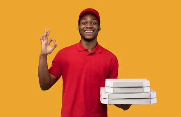 Un repartidor negro sosteniendo cajas de pizza, mostrando un gesto aceptable — Foto de Stock