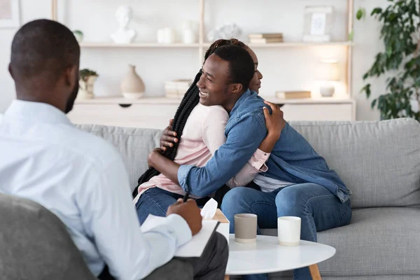 Paartherapie. Glückliche schwarze Eheleute umarmen sich nach Versöhnung im Büro der Eheberater — Stockfoto