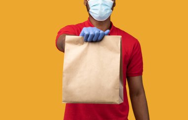 Tıbbi maskeli ve eldiven taşıyan siyah teslimatçı.