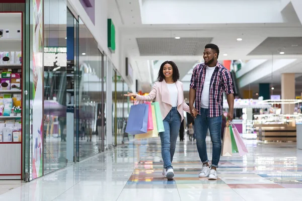 Gelukkig Afrikaans-Amerikaans paar doet winkelen in winkelcentrum samen, kijken naar vitrines — Stockfoto