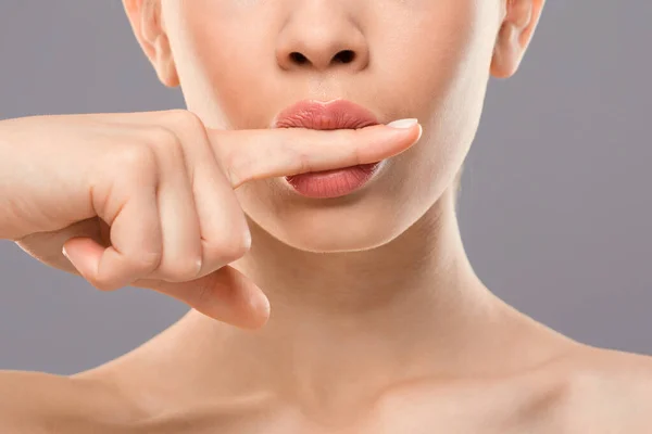 Обрезанная женщина, держащая палец между губ — стоковое фото