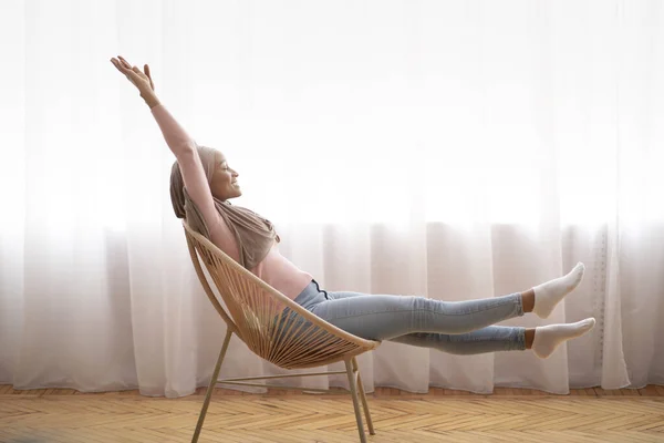 Fauler erholsamer Tag. Seitenansicht von Millennial schwarze Frau im Hijab Stretching in bequemen Sessel zu Hause, Kopierraum — Stockfoto