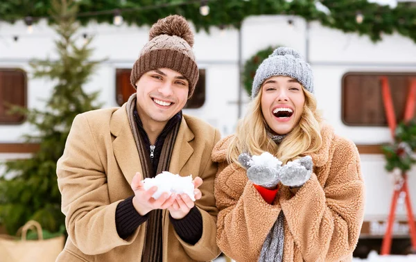 Молодая романтическая пара, играющая со снегом, развлекающаяся на свежем воздухе в зимний день — стоковое фото