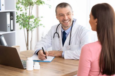 Erkek deneyimli doktor kadın hastasıyla konuşuyor.