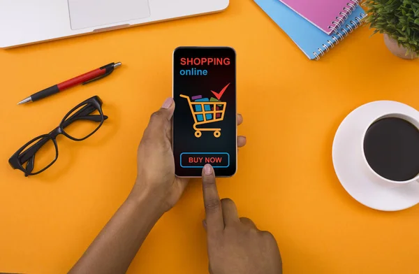 Nero signora utilizzando il telefono per lo shopping online, sfondo giallo, primo piano — Foto Stock