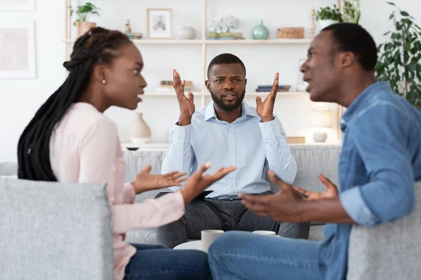 Psicólogo negro irritado assistindo casal discutindo durante sessão de terapia conjugal — Fotografia de Stock