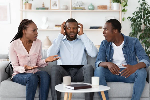 震惊的黑人婚姻顾问在治疗期间坐在争吵的配偶之间 — 图库照片
