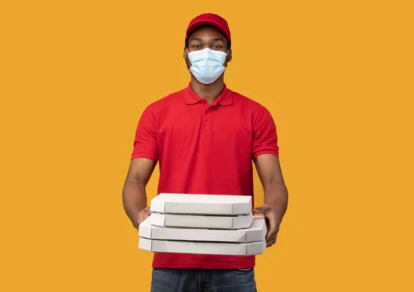 Repartidor negro en máscara médica sosteniendo cajas de pizza —  Fotos de Stock