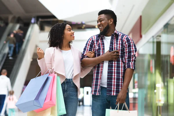 Portret van gelukkig zwart paar met boodschappentassen wandelen in warenhuis — Stockfoto