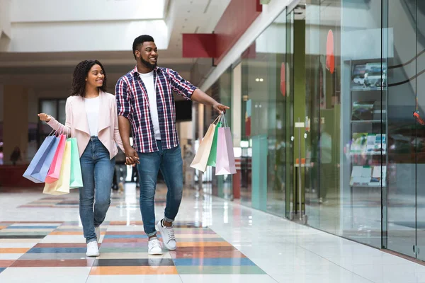 Homem negro feliz mostrando algo na vitrine para sua namorada — Fotografia de Stock