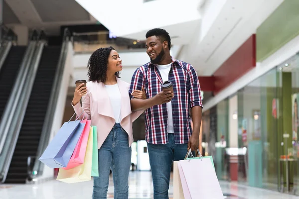 Vásárló szerelmesek. Fekete pár sétál a kávé és a bevásárló táskák a Mall — Stock Fotó