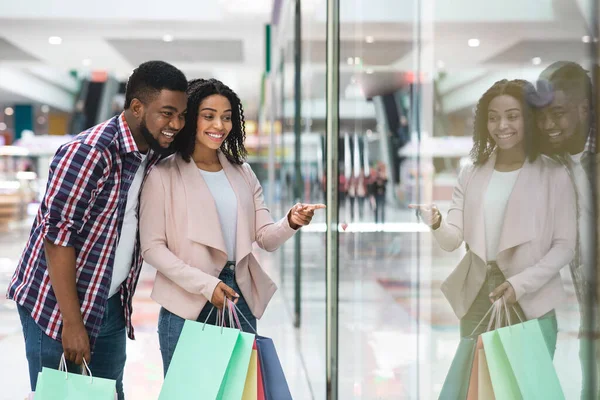Gelukkig zwart echtgenoten genieten samen winkelen in winkelcentrum, kijken naar showcase — Stockfoto