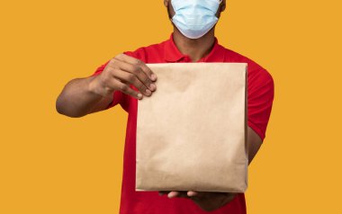 Siyah teslimatçı, tıbbi maske takıyor.