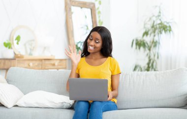 Uzaktan iletişim konsepti. Bilgisayarlı neşeli siyahi kadın evinden ailesiyle, arkadaşlarıyla ya da meslektaşlarıyla konuşuyor.