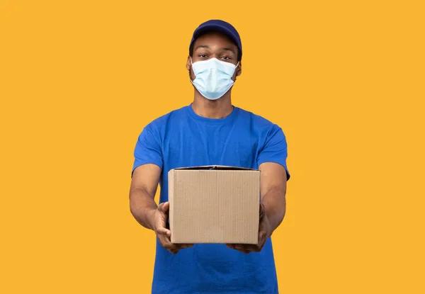 Svart leverans man i medicinsk mask innehav box — Stockfoto