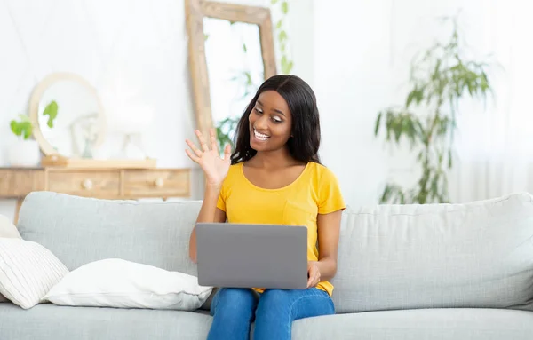 Conceito de comunicação remota. Mulher negra alegre com laptop conversando com a família, amigos ou coleagues on-line de casa — Fotografia de Stock