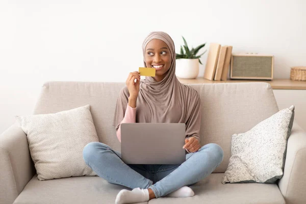 İnternetten kredi kartı ve laptopla alışveriş yapan tesettürlü siyah kadın portresi. — Stok fotoğraf