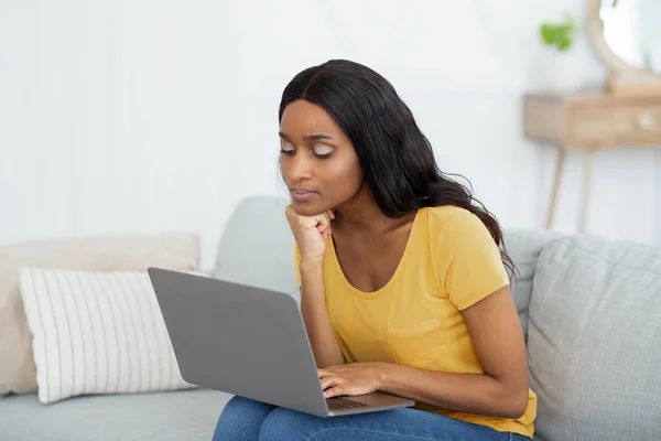 Ragionevole signora afroamericana utilizzando il computer portatile per guardare video educativi o partecipare a webinar da casa — Foto Stock