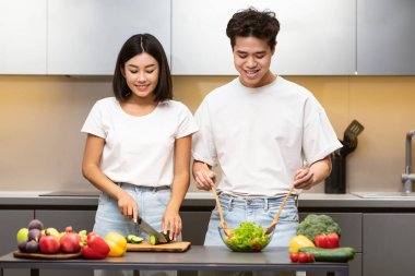 Neşeli Koreli çift mutfakta taze sebze salatası yapıyor.