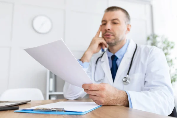 Retrato del médico pensativo leyendo informe médico — Foto de Stock