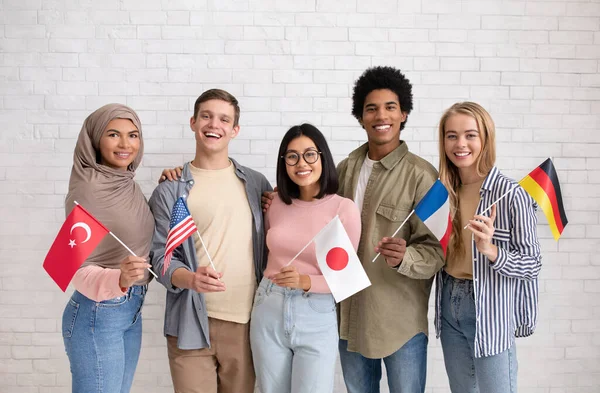 Giovani studenti multietnici con bandiere di diversi paesi pronti a studiare — Foto Stock