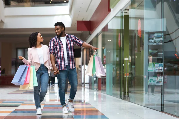 Zwarte Vrijdag Verkoop. Gelukkig Afrikaans paar wandelen met boodschappentassen in winkelcentrum — Stockfoto