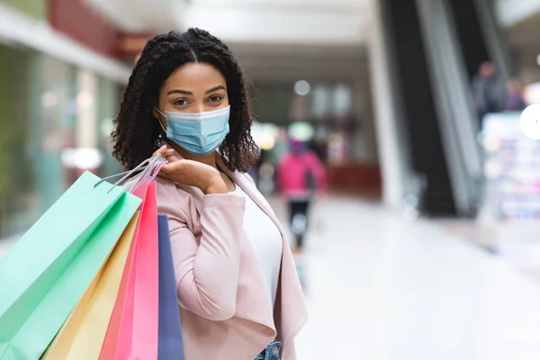 Coronavirus Shopping. Mulher negra com máscara médica na cara posando no shopping — Fotografia de Stock