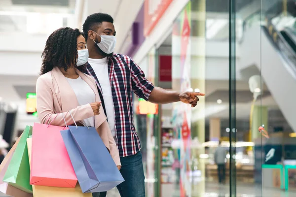Winkelen tijdens een coronavirus uitbraak. zwart paar dragen medische gezicht maskers in winkelcentrum — Stockfoto