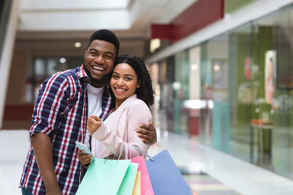 Cónyuges negros alegres posando en el centro comercial después de compras exitosas, haciendo compras juntos —  Fotos de Stock