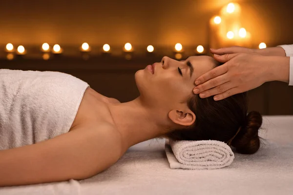 Terapeuta irreconhecível massageando a testa da mulher dormindo, vista lateral — Fotografia de Stock