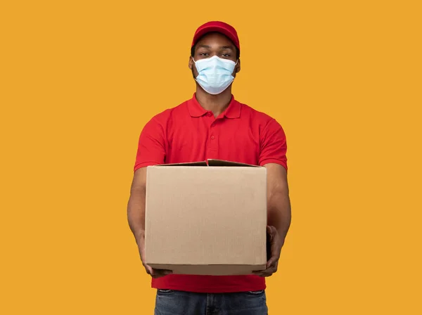 Svart leverans man i medicinsk mask ger box — Stockfoto