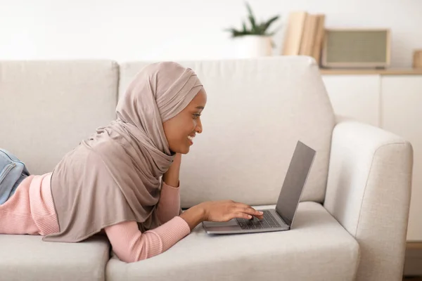 Siyah kadının tesettürdeki boş ekranlı dizüstü bilgisayarını kullanırken yan görünümü, boşluğu kopyala — Stok fotoğraf