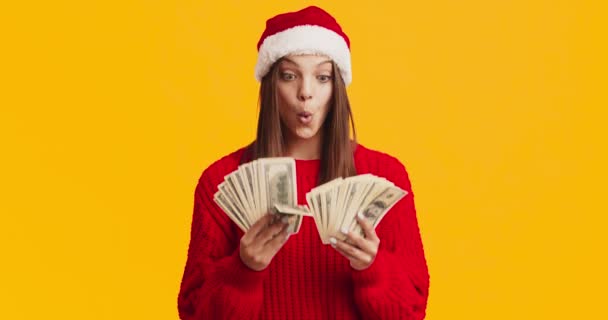 Mujer bonita en suéter rojo y sombrero de Santa celebración de billetes de dinero, listo para comprar regalos de Navidad — Vídeos de Stock