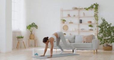 Fitness siyahi kadın evde burpee egzersizi yapıyor, şınav çekiyor ve zıplama egzersizi yapıyor.