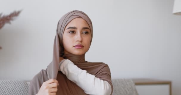 Cappelli islamici tradizionali. Giovane donna musulmana che indossa hijab, seduta sul divano a casa — Video Stock