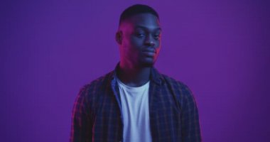 Kendinden emin Afrikalı Amerikalı adam kameraya dönüp işaret veriyor. Tamam işareti, neon ışıkları.