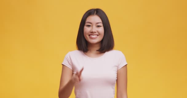 Junge positive asiatische Frau zeigt Friedensgeste, drückt Spaß und Glück aus, orangefarbener Studiohintergrund — Stockvideo