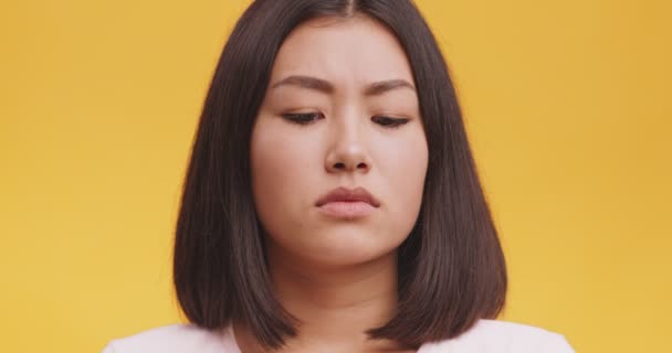 Недовольство азиатской женщины хмурящееся лицо, запах что-то ужасное, чувство отвращения, оранжевый фон студии — стоковое видео