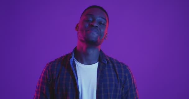 Stilfuldt portræt af ung afrikaner amerikansk mand griner over neonlys baggrund, føler lykke – Stock-video