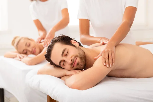 Marido Relajante durante el masaje de parejas con su esposa en el salón de spa —  Fotos de Stock