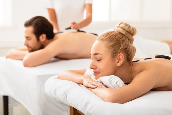 Casal recebendo massagem de pedra quente desfrutando de tratamento de beleza no interior — Fotografia de Stock